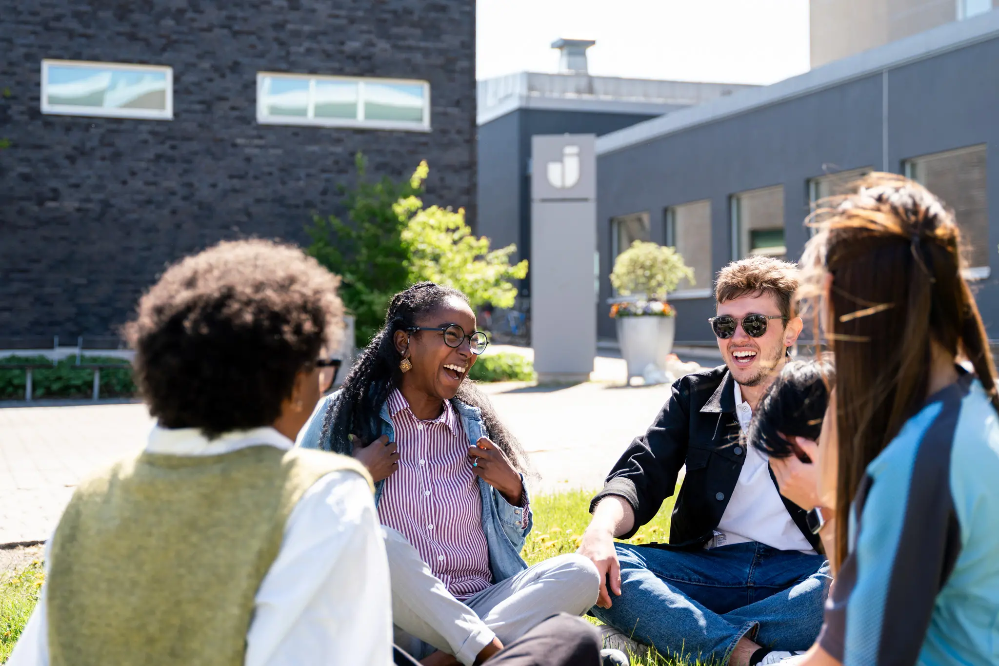 En grupp studenter skrattar och ler på campusområdet