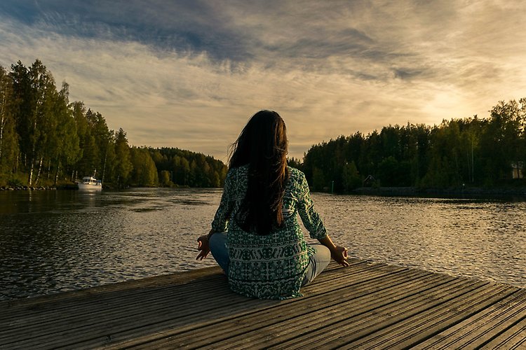 A woman sitting on a jetty doing yoga