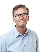 Man wearing glasses and a light blue collared shirt, facing forward and smiling slightly, posed against a white background.
